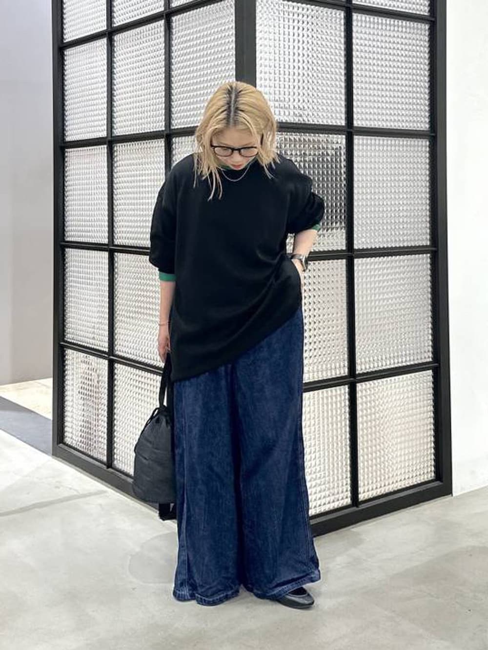 ブラック系のショルダーバッグ、ブラック系のTシャツ/カットソー、ブルー系のデニムパンツを着用したレディースの秋コーディネートの2枚目の写真