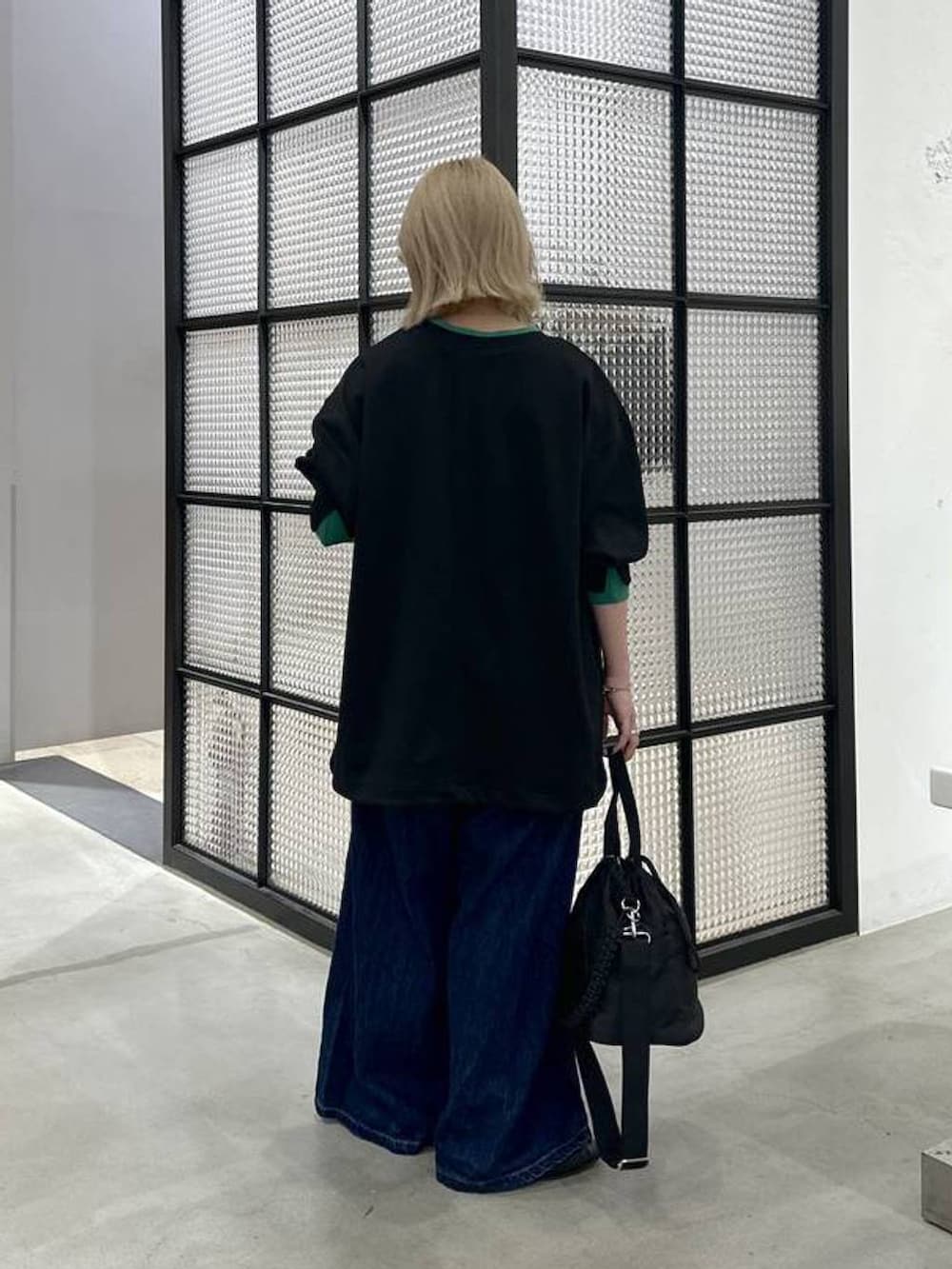 ブラック系のショルダーバッグ、ブラック系のTシャツ/カットソー、ブルー系のデニムパンツを着用したレディースの秋コーディネートの4枚目の写真