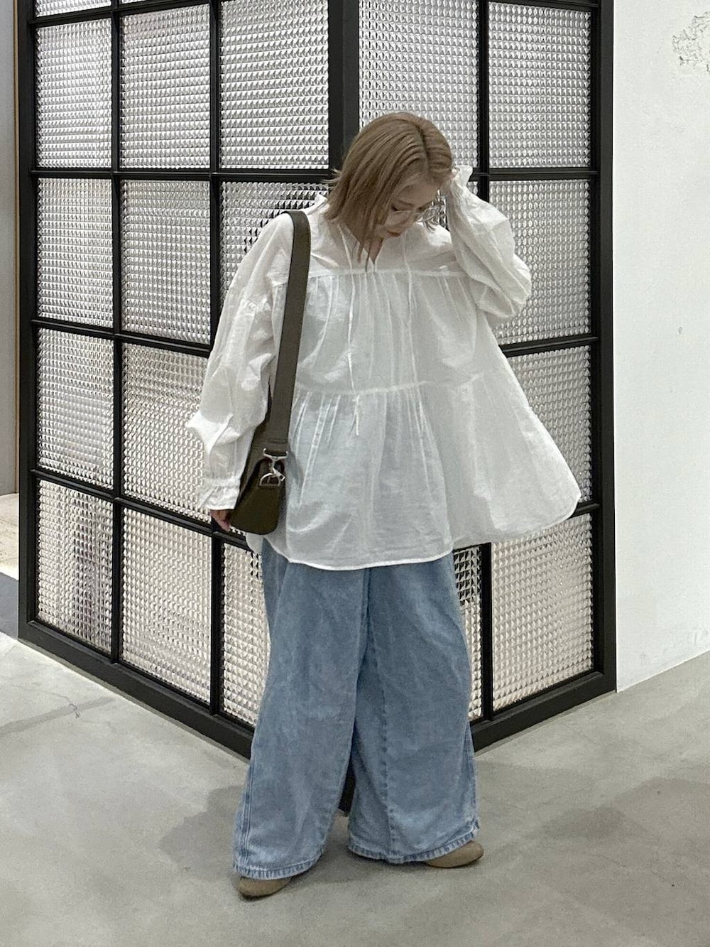 ブラウン系のショルダーバッグ、ブルー系のデニムパンツ、ベージュ系のパンプスを着用したレディースの春コーディネートの2枚目の写真