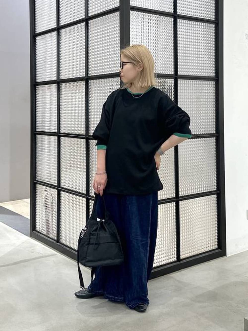 ブラック系のショルダーバッグ、ブラック系のTシャツ/カットソー、ブルー系のデニムパンツを着用したレディースの秋コーディネートの3枚目の写真