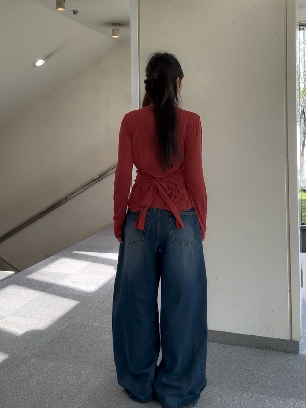 レッド系のTシャツ/カットソー、ブルー系のデニムパンツ、ブラック系のスニーカーを着用したレディースの春コーディネートの3枚目の写真