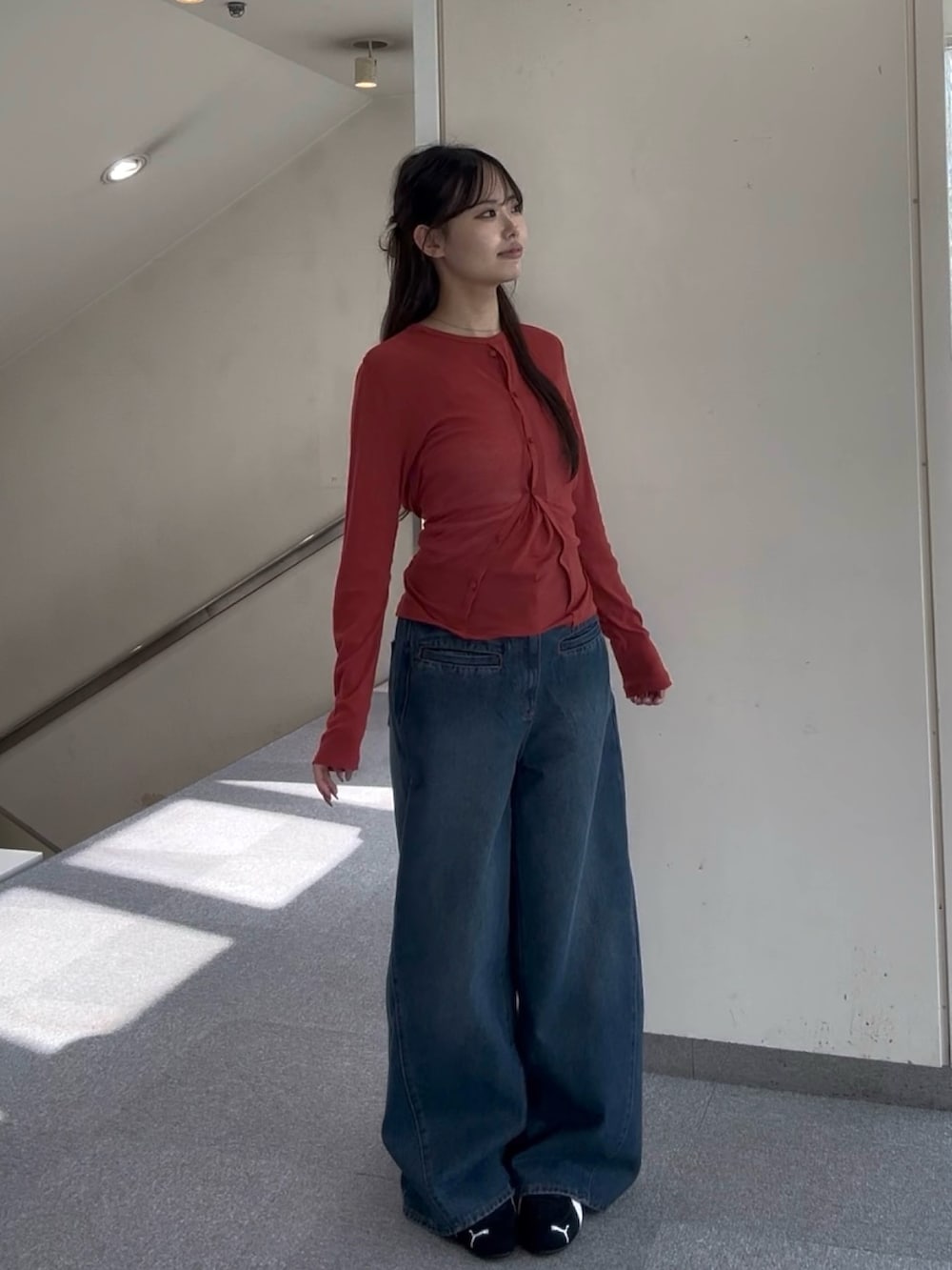 レッド系のTシャツ/カットソー、ブルー系のデニムパンツ、ブラック系のスニーカーを着用したレディースの春コーディネートの2枚目の写真