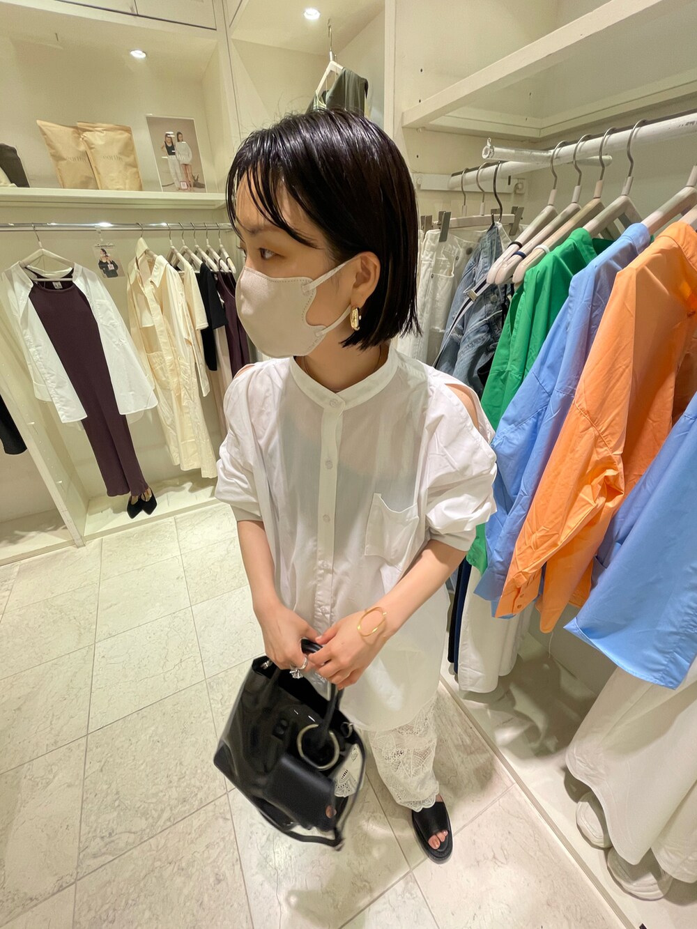 ブラック系のショルダーバッグ、ホワイト系のシャツ/ブラウス、ホワイト系のデニムパンツを着用したレディースの夏コーディネートの3枚目の写真