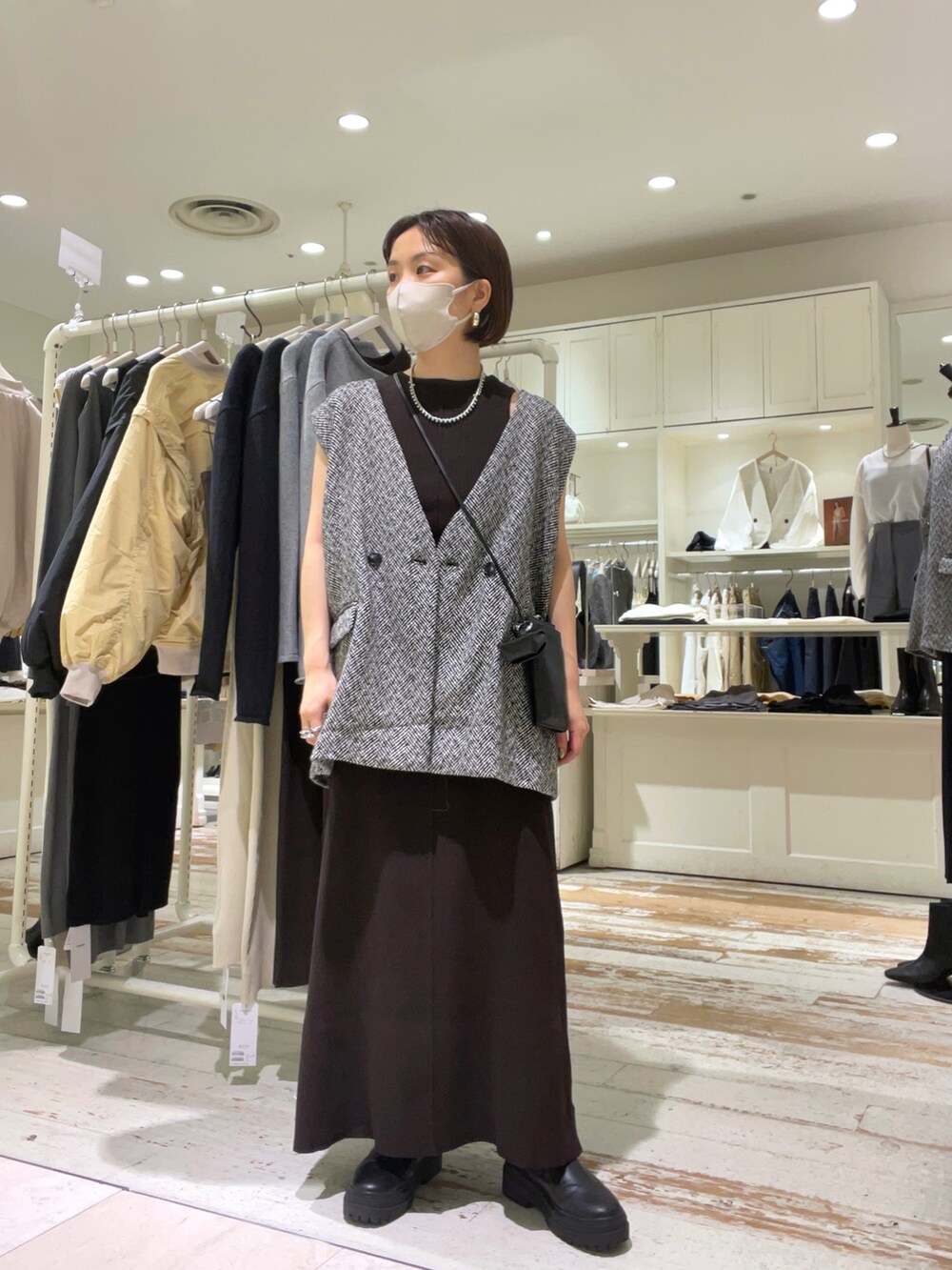 ブラウン系のワンピース、ブラック系のショルダーバッグ、ブラック系のベストを着用したレディースの秋コーディネートの4枚目の写真