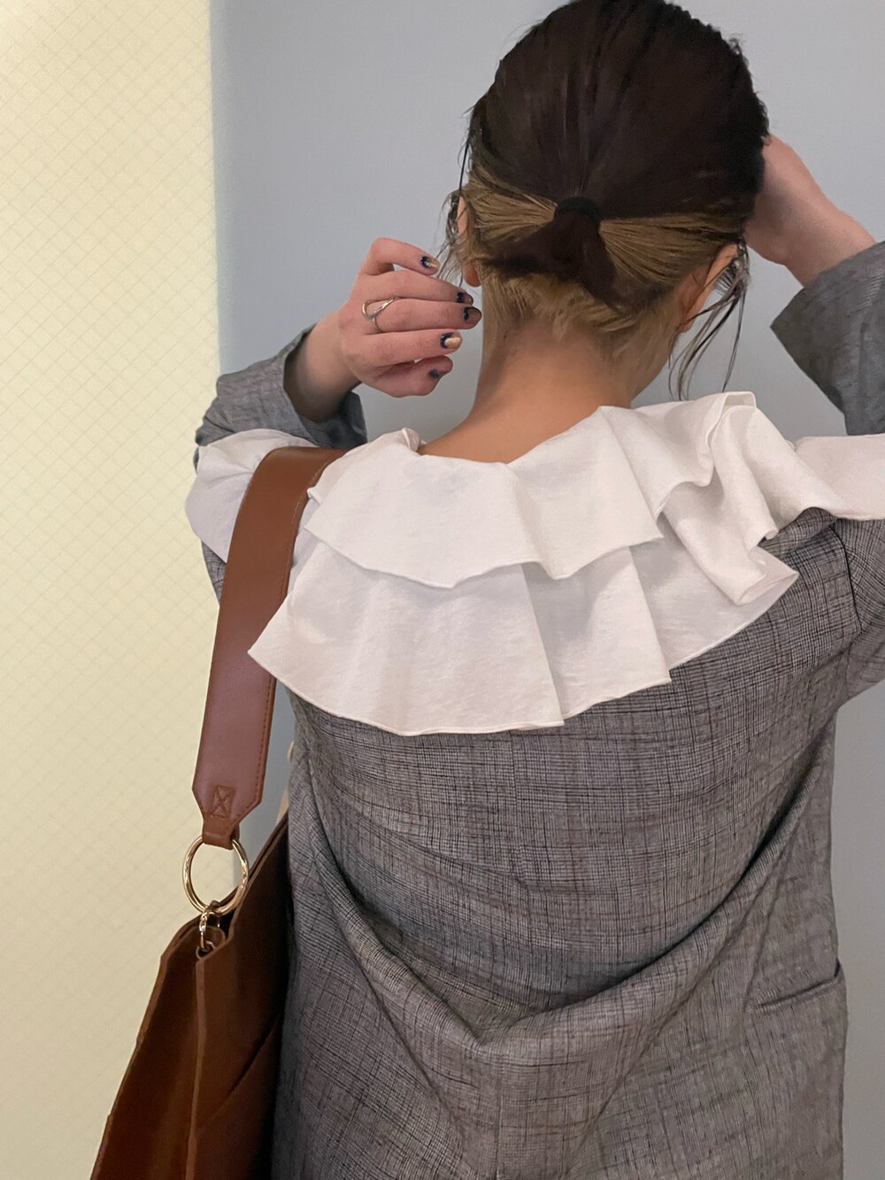 ブラック系のテーラードジャケット、ブラウン系のトートバッグ、ホワイト系のローファーを着用したレディースの冬コーディネートの2枚目の写真