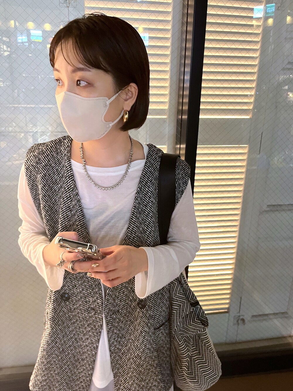ホワイト系のTシャツ/カットソー、ブラック系のベスト、グレー系のスカートを着用したレディースの秋コーディネートの5枚目の写真