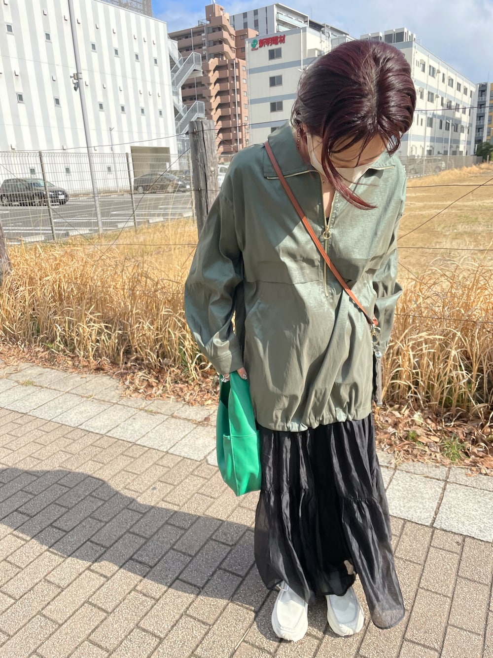 グリーン系のニット/セーター、ブラック系のスカートを着用したレディースの春コーディネートの4枚目の写真