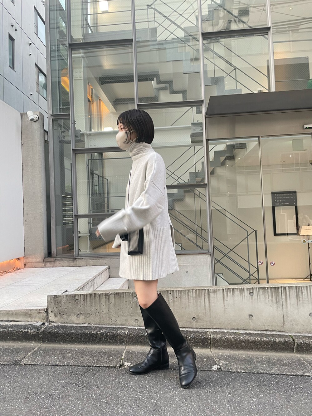 ホワイト系のニット/セーター、ブラック系のショルダーバッグ、ブラック系のブーツを着用したレディースの秋コーディネートの2枚目の写真