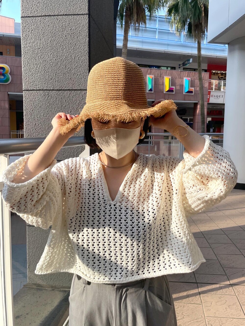 ホワイト系のニット/セーター、グレー系のスラックス、ブラック系のサンダルを着用したレディースの夏コーディネートの2枚目の写真