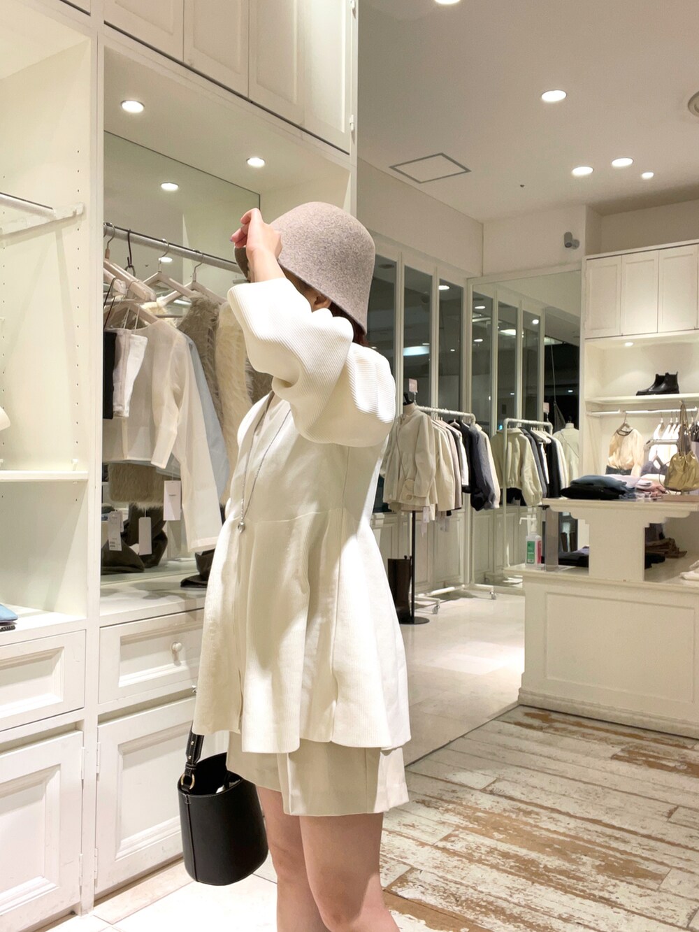 ホワイト系のニット/セーター、ブラック系のハンドバッグ、ブラック系のブーツを着用したレディースの秋コーディネートの3枚目の写真