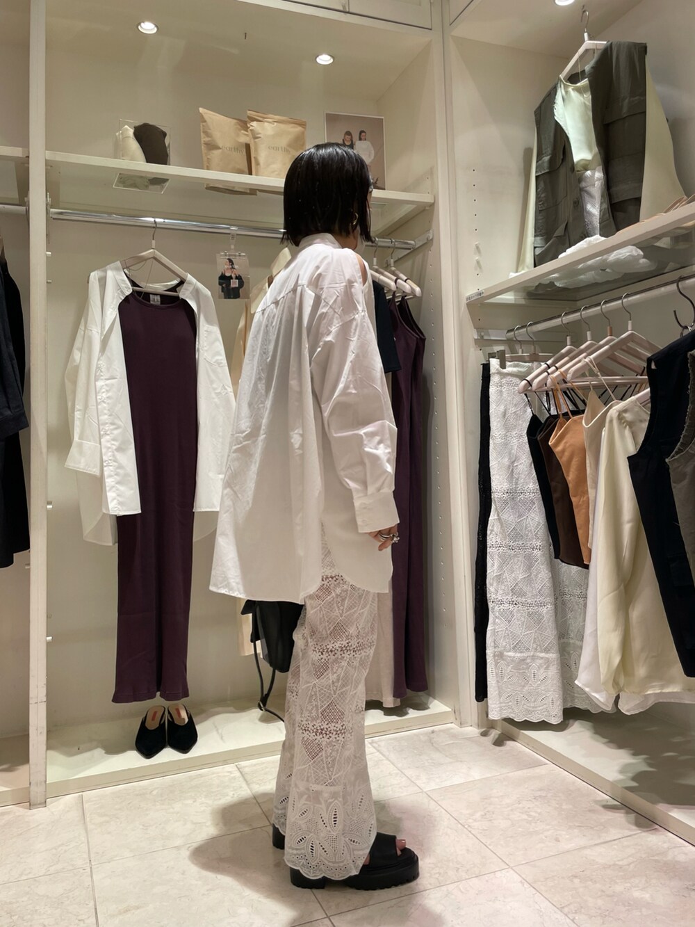 ブラック系のショルダーバッグ、ホワイト系のシャツ/ブラウス、ホワイト系のデニムパンツを着用したレディースの夏コーディネートの2枚目の写真