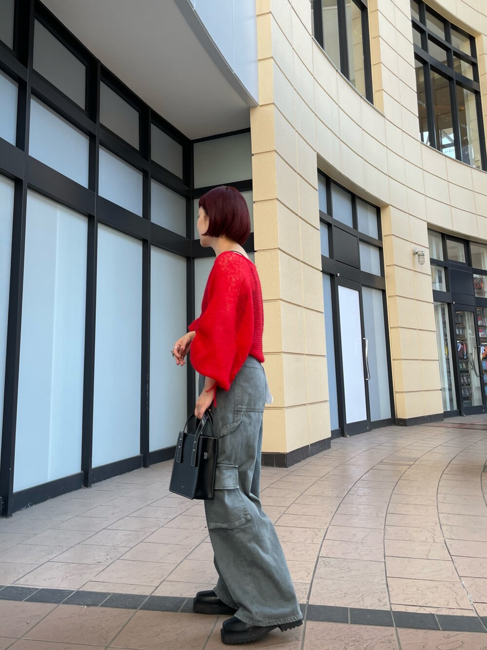 レッド系のニット/セーター、ブラック系のキャミソール、グレー系のデニムパンツを着用したレディースの夏コーディネートの5枚目の写真