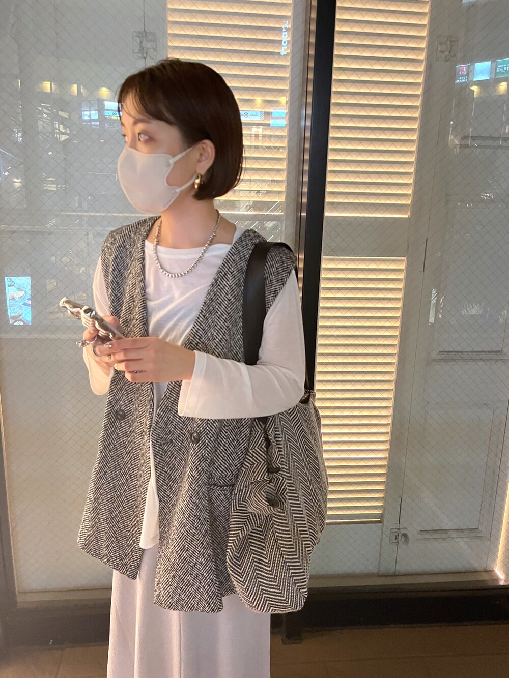 ホワイト系のTシャツ/カットソー、ブラック系のベスト、グレー系のスカートを着用したレディースの秋コーディネートの2枚目の写真