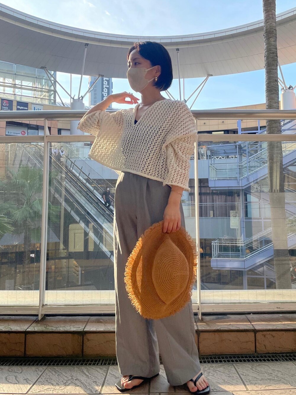 ホワイト系のニット/セーター、グレー系のスラックス、ブラック系のサンダルを着用したレディースの夏コーディネートの5枚目の写真