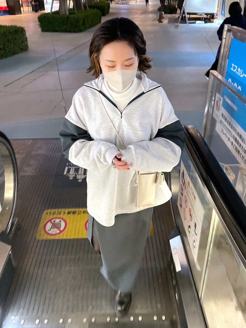 グレー系のスウェット、ホワイト系のニット/セーター、ホワイト系のショルダーバッグを着用したレディースの冬コーディネートの3枚目の写真