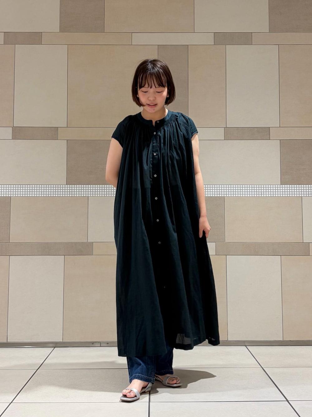グリーン系のワンピース、ブルー系のデニムパンツ、シルバー系のサンダルを着用したレディースの夏コーディネートの3枚目の写真