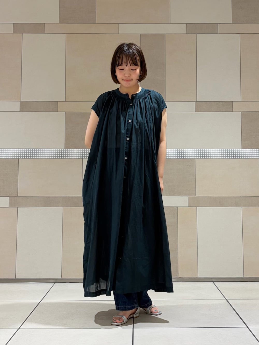 グリーン系のワンピース、ブルー系のデニムパンツ、シルバー系のサンダルを着用したレディースの夏コーディネートの2枚目の写真