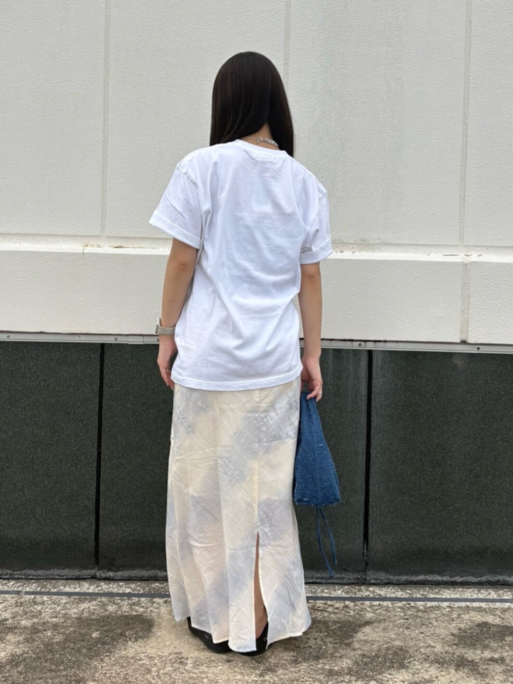 ホワイト系のTシャツ/カットソー、ブルー系のスカート、ブルー系のハンドバッグを着用したレディースの夏コーディネートの3枚目の写真