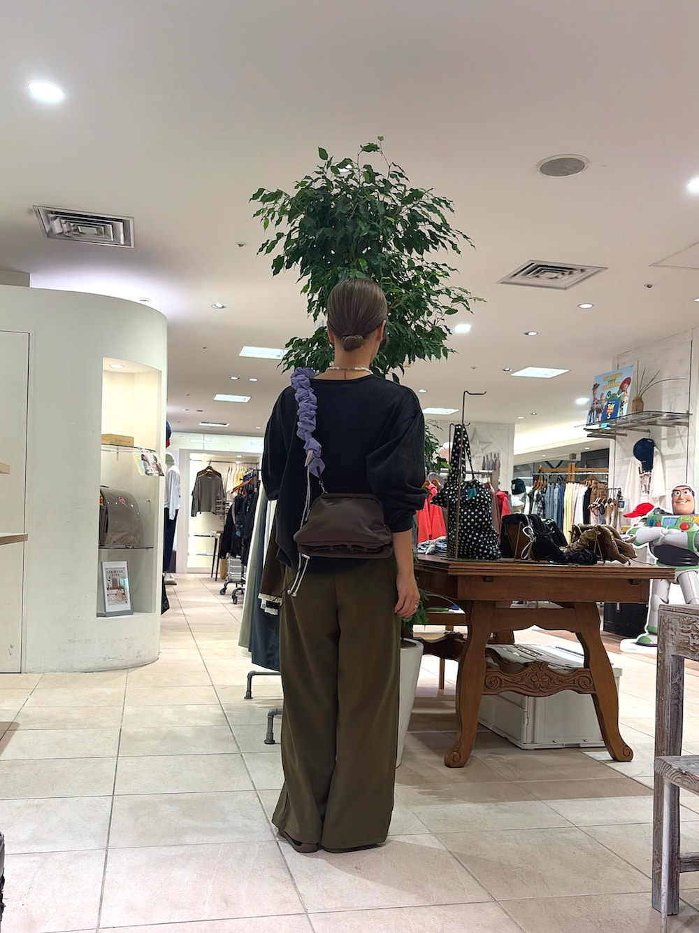 ブラック系のTシャツ/カットソー、ブラウン系のショルダーバッグ、グリーン系のスラックスを着用したレディースの秋コーディネートの2枚目の写真