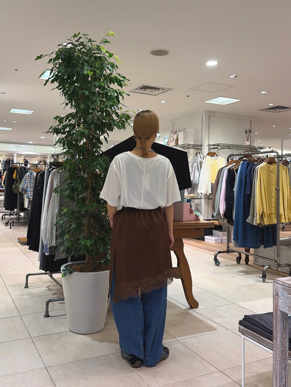 ホワイト系のTシャツ/カットソー、ブルー系のデニムパンツ、ブラウン系のスカートを着用したレディースの春コーディネートの2枚目の写真