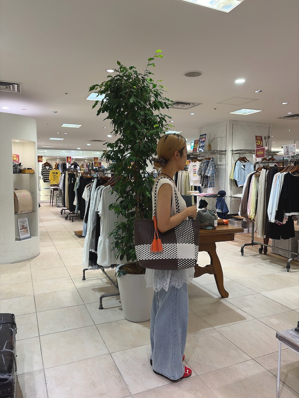 ホワイト系のベスト、ブルー系のデニムパンツ、ブラウン系のトートバッグを着用したレディースの夏コーディネートの3枚目の写真