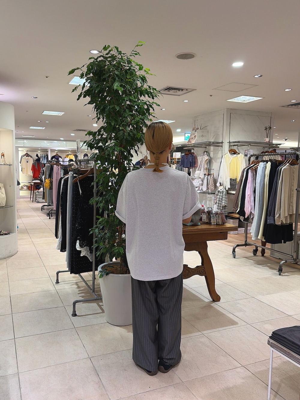 グレー系のTシャツ/カットソー、ブラック系のショルダーバッグ、グレー系のスラックスを着用したレディースの春コーディネートの2枚目の写真