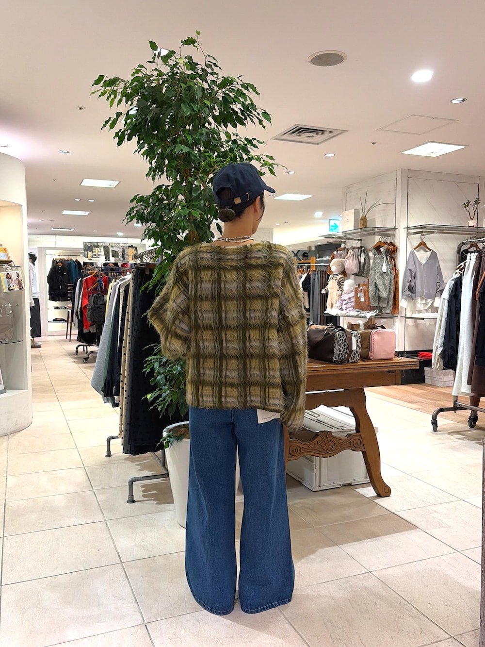 グリーン系のカーディガン/ボレロ、ブルー系のデニムパンツ、ブルー系のキャップを着用したレディースの秋コーディネートの2枚目の写真