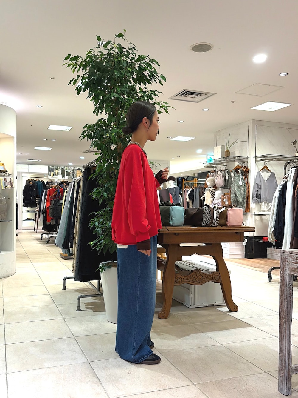 レッド系のTシャツ/カットソー、イエロー系のショルダーバッグ、ブルー系のデニムパンツを着用したレディースの秋コーディネートの2枚目の写真