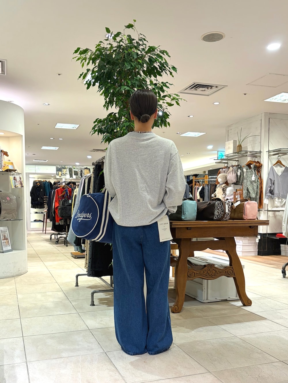グレー系のスウェット、ブルー系のボストンバッグ、ブルー系のデニムパンツを着用したレディースの秋コーディネートの3枚目の写真