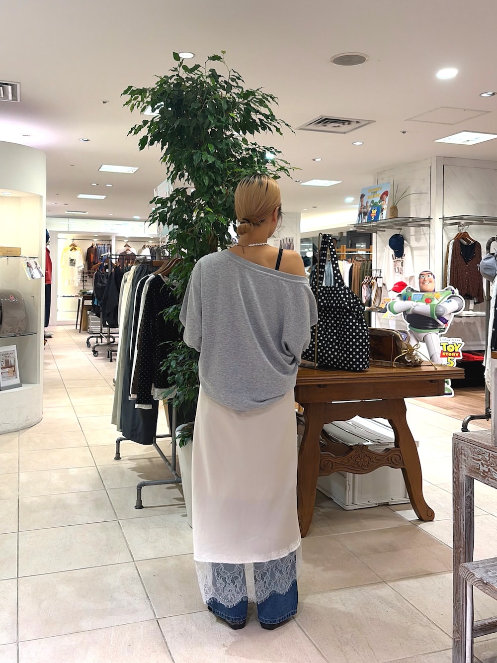 ホワイト系のスカート、ブルー系のデニムパンツ、グレー系のスウェットを着用したレディースの秋コーディネートの2枚目の写真