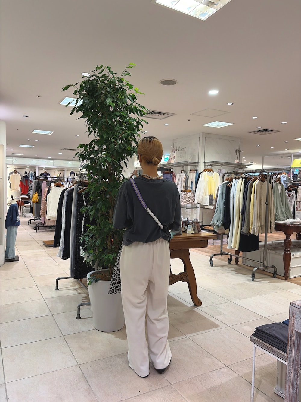 グレー系のTシャツ/カットソー、グレー系のショルダーバッグ、ホワイト系のスラックスを着用したレディースの春コーディネートの2枚目の写真