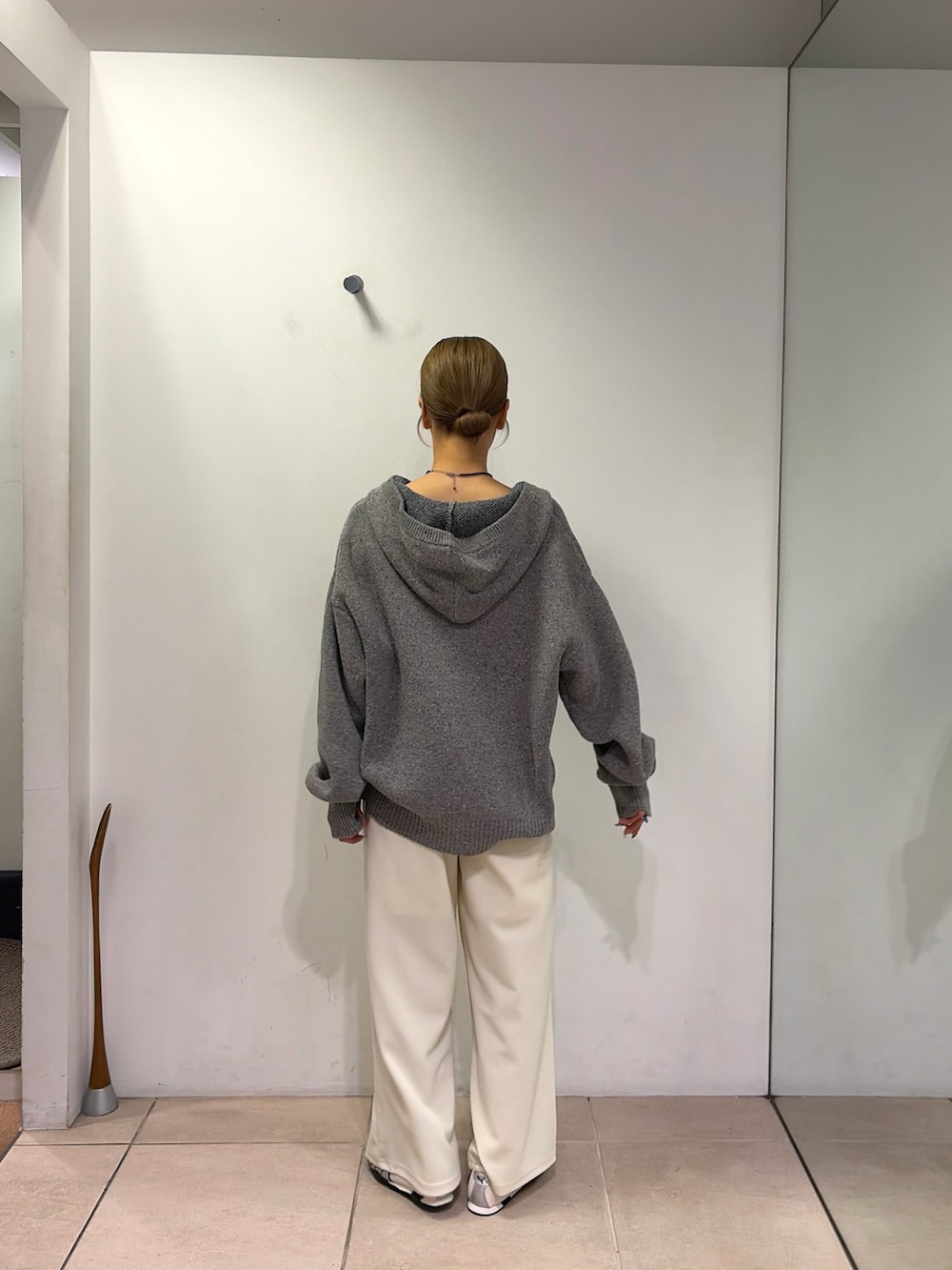 グレー系のパーカー、ホワイト系のスラックスを着用したレディースの秋コーディネートの2枚目の写真