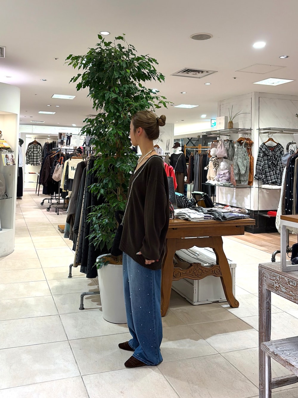 ブルー系のデニムパンツ、ブラウン系のカーディガン/ボレロ、ブラウン系のパンプスを着用したレディースの秋コーディネートの3枚目の写真