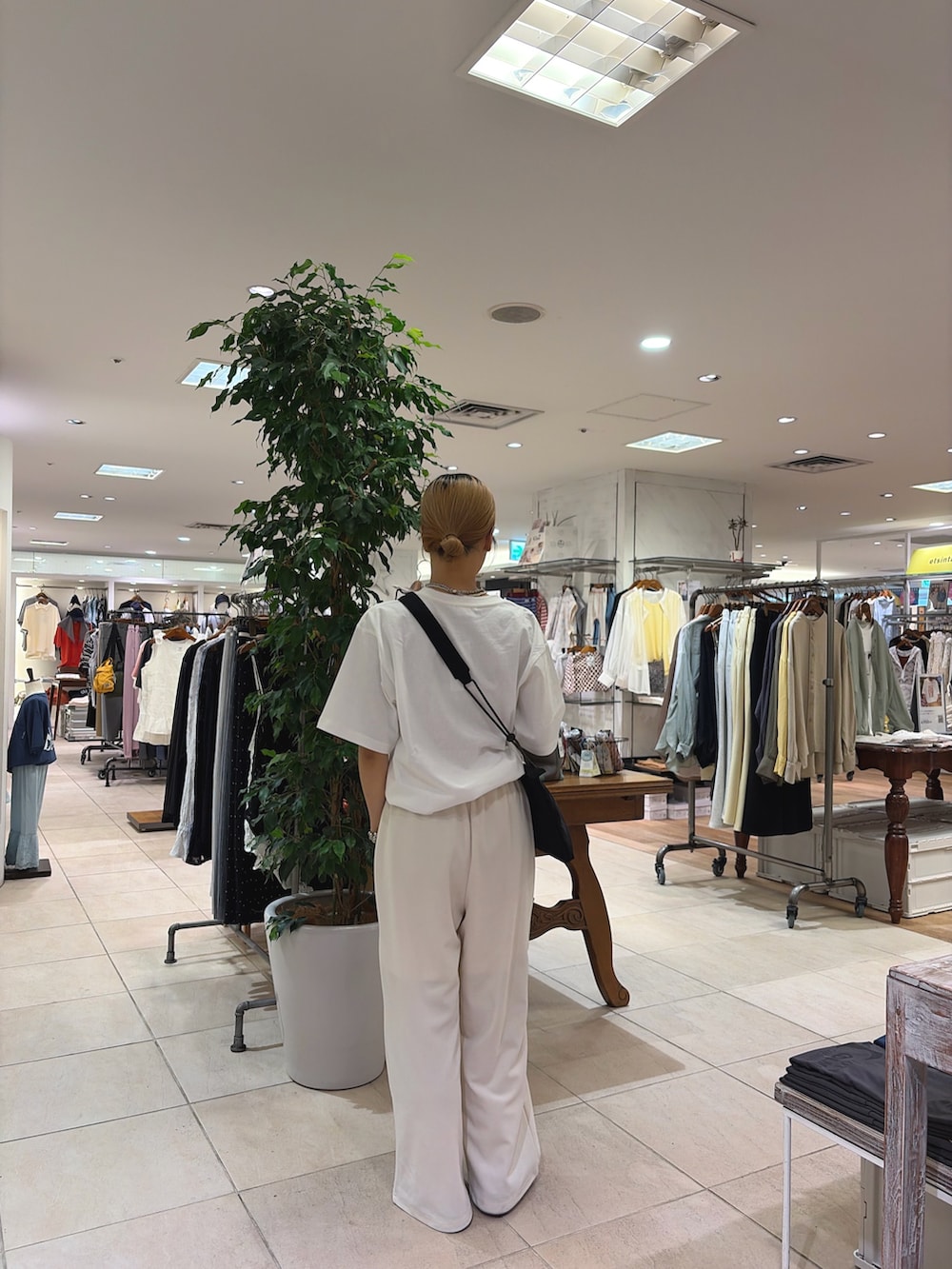 ホワイト系のTシャツ/カットソー、ホワイト系のスラックス、ブラック系のショルダーバッグを着用したレディースの春コーディネートの2枚目の写真