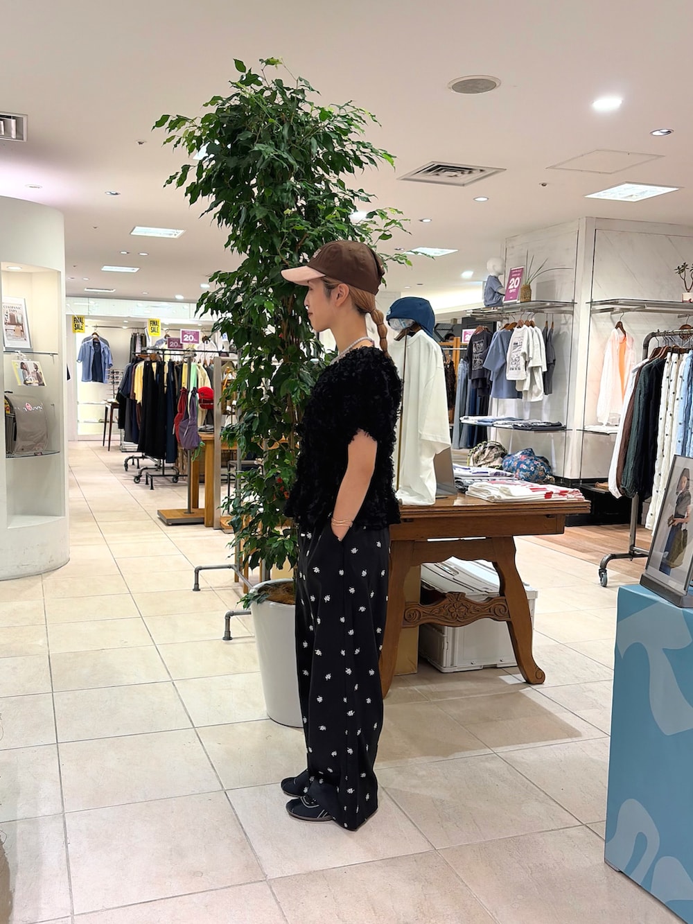 ブラック系のシャツ/ブラウス、ブラック系のスラックス、ブラウン系のキャップを着用したレディースの夏コーディネートの2枚目の写真