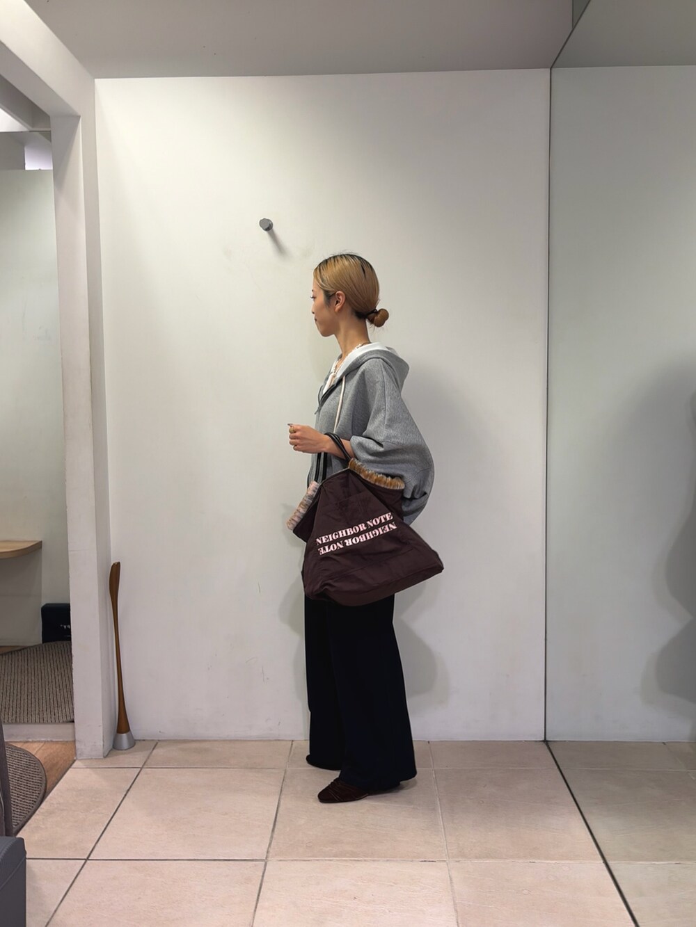 グレー系のパーカー、ブラック系のスラックス、ブラウン系のパンプスを着用したレディースの秋コーディネートの2枚目の写真