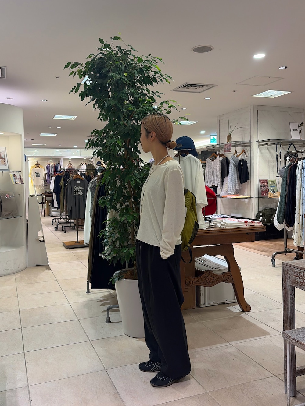 ホワイト系のTシャツ/カットソー、グリーン系のバックパック/リュック、ブラック系のその他パンツを着用したレディースの秋コーディネートの2枚目の写真