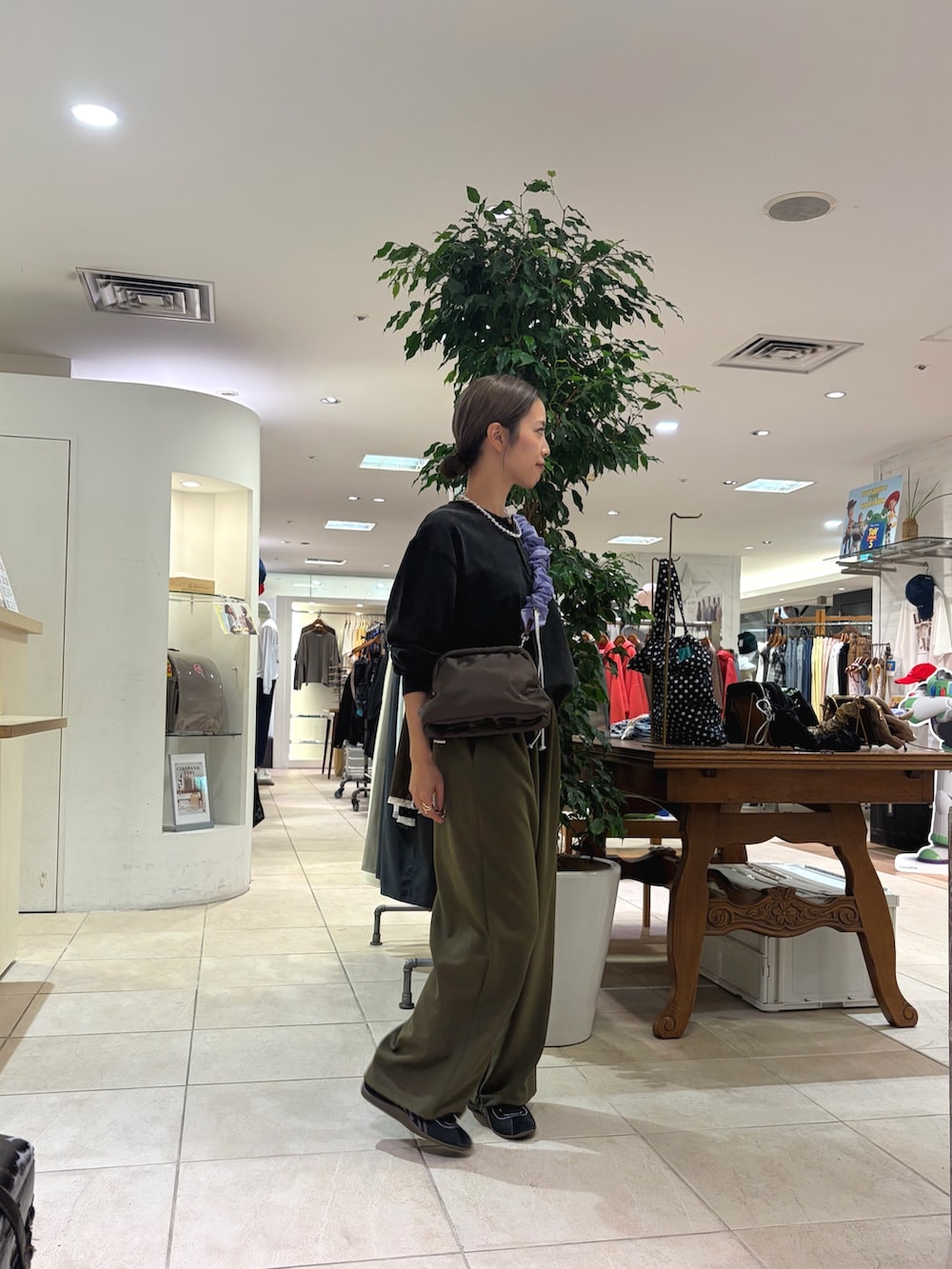 ブラック系のTシャツ/カットソー、ブラウン系のショルダーバッグ、グリーン系のスラックスを着用したレディースの秋コーディネートの4枚目の写真