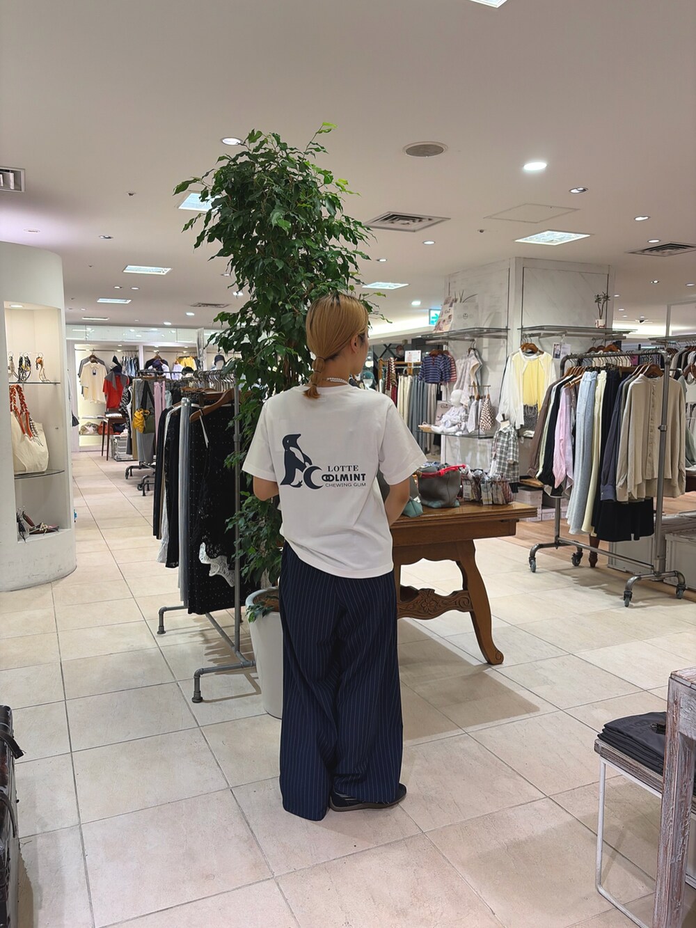 ホワイト系のTシャツ/カットソー、ブルー系のスラックス、ブラック系のショルダーバッグを着用したレディースの春コーディネートの2枚目の写真