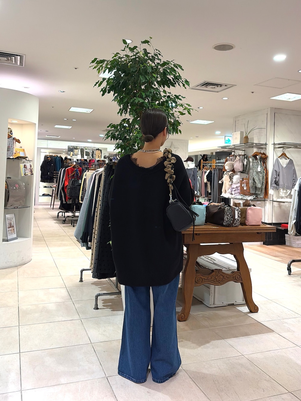 ブラック系のニット/セーター、ブラック系のショルダーバッグ、ブルー系のデニムパンツを着用したレディースの秋コーディネートの2枚目の写真