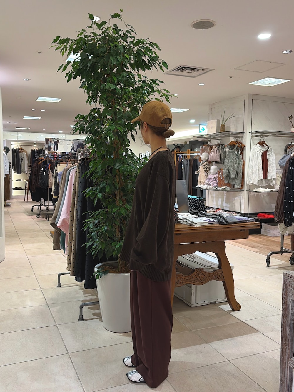 ブラウン系のカーディガン/ボレロ、ブラウン系のスラックス、イエロー系のキャップを着用したレディースの秋コーディネートの2枚目の写真