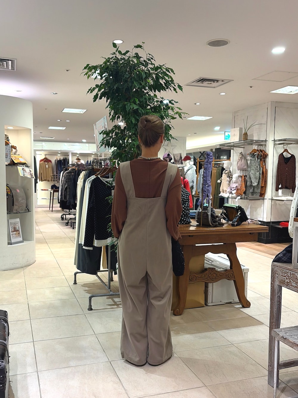 ベージュ系のサロペット/オーバーオール、ブラウン系のTシャツ/カットソー、ブラック系のショルダーバッグを着用したレディースの秋コーディネートの3枚目の写真