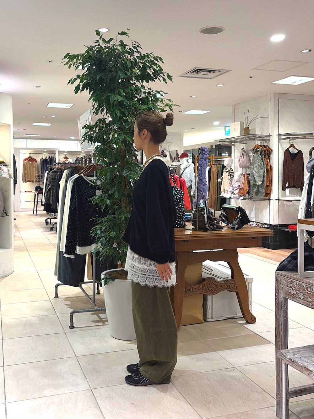 ホワイト系のチュニック、ブラック系のカーディガン/ボレロ、グリーン系のその他パンツを着用したレディースの秋コーディネートの2枚目の写真