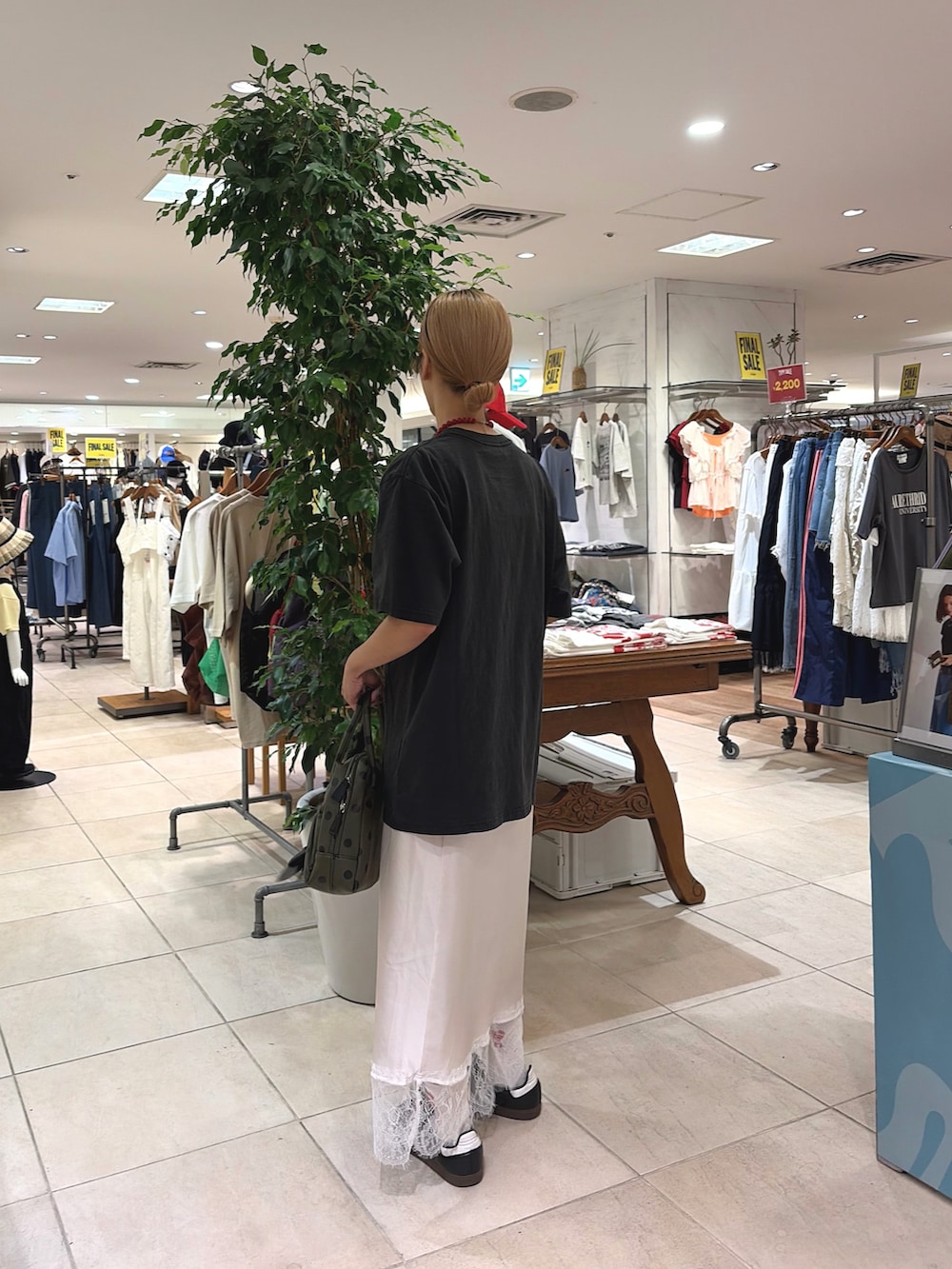 ブラック系のTシャツ/カットソー、ホワイト系のスカート、グリーン系のショルダーバッグを着用したレディースの夏コーディネートの2枚目の写真