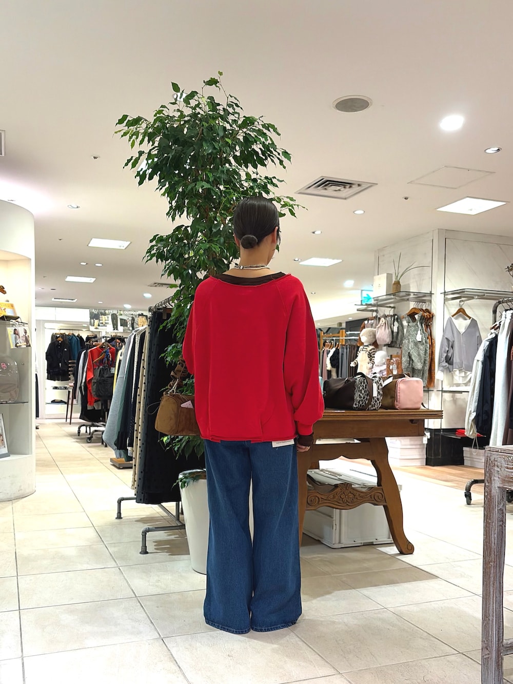 レッド系のTシャツ/カットソー、イエロー系のショルダーバッグ、ブルー系のデニムパンツを着用したレディースの秋コーディネートの3枚目の写真
