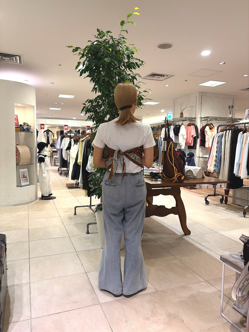 ブラウン系のトートバッグ、ブルー系のデニムパンツ、レッド系のバンダナ/スカーフを着用したレディースの夏コーディネートの3枚目の写真