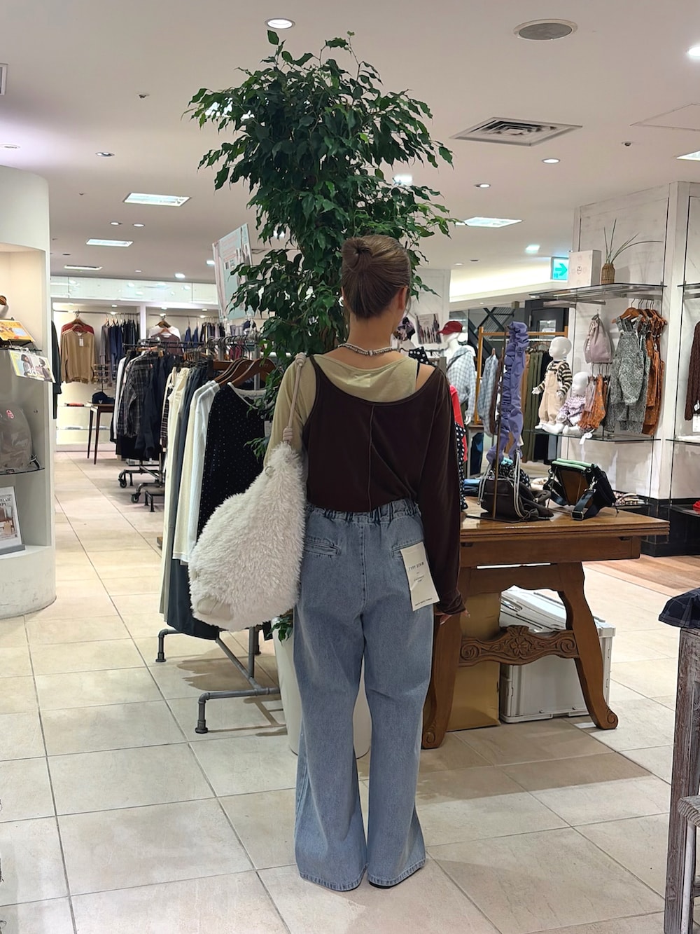 ブラウン系のTシャツ/カットソー、ホワイト系のショルダーバッグ、ブルー系のデニムパンツを着用したレディースの秋コーディネートの2枚目の写真