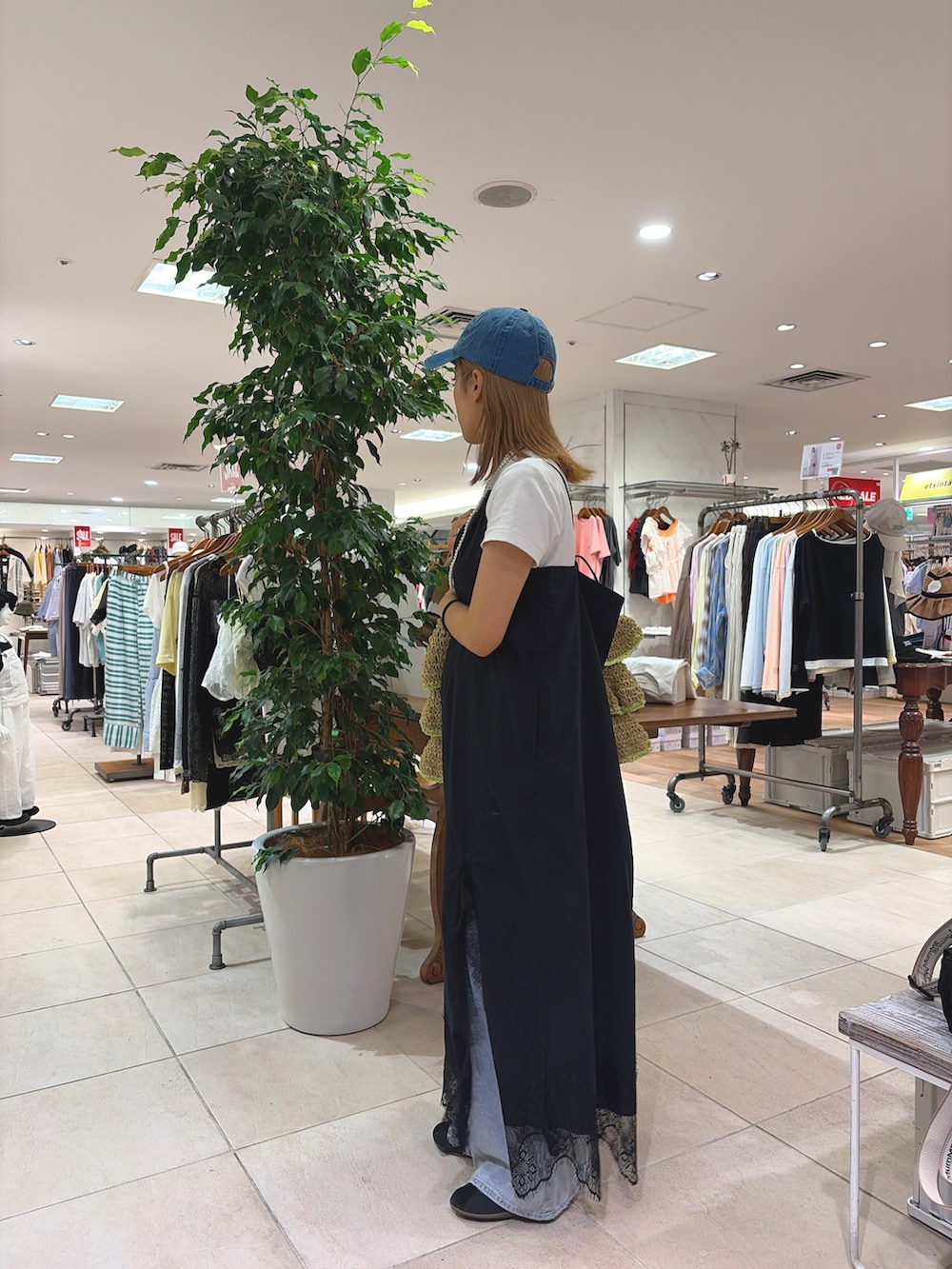 ブラック系のワンピース、ベージュ系のトートバッグ、ブルー系のデニムパンツを着用したレディースの夏コーディネートの3枚目の写真