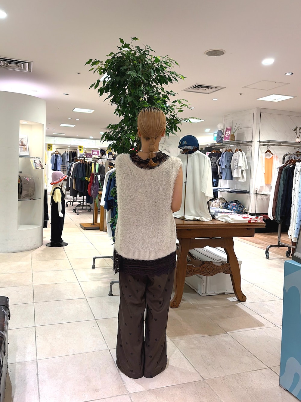 ブラック系のチュニック、ホワイト系のベスト、ブラウン系のスラックスを着用したレディースの夏コーディネートの3枚目の写真