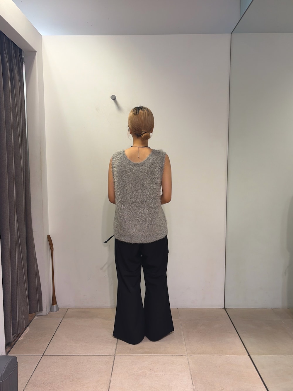 グレー系のベスト、ブラック系のデニムパンツ、ブラック系のショルダーバッグを着用したレディースの夏コーディネートの2枚目の写真